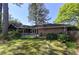 Beautiful backyard with mature trees, lush lawn, brick accents, and wooden deck with lattice fence at 1629 Anita Ne Pl, Atlanta, GA 30306
