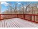 Exterior wooden deck with red railings and snowy planks, overlooking wooded area at 2155 Washington Dr, Douglasville, GA 30135