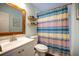 Bright bathroom featuring a colorful shower curtain, floating shelves, and framed mirror at 2232 Dunseath Ave # 407, Atlanta, GA 30318