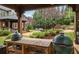 Outdoor kitchen with wood table and green egg smokers and view of backyard landscaping, pool and trees at 1319 Glen Cedars Dr, Smyrna, GA 30126