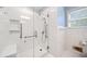 Modern shower with glass door, tiled walls, built-in seat, and grab bars for safety and accessibility at 1478 Biltmore Ne Dr, Atlanta, GA 30329