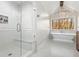 Bright bathroom featuring a glass-enclosed shower, soaking tub, chandelier, and a large window at 2100 Kings Valley Dr, Lawrenceville, GA 30043