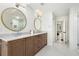 Bathroom featuring double vanity with granite countertop, oval mirrors, white walls, and grey patterned tile flooring at 2100 Kings Valley Dr, Lawrenceville, GA 30043