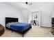 Well-lit bedroom featuring a black bed frame, blue bedding, a window with black blinds, and neutral carpet at 2100 Kings Valley Dr, Lawrenceville, GA 30043