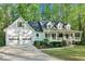 Beautiful home exterior featuring a two-car garage, mature trees, a front lawn, and a front porch at 2100 Kings Valley Dr, Lawrenceville, GA 30043