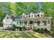 Charming home exterior featuring a welcoming front porch, well-manicured lawn and beautiful, mature trees at 2100 Kings Valley Dr, Lawrenceville, GA 30043