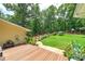 Expansive backyard featuring a well-maintained lawn, wood fence, mature trees, and a charming wooden deck area at 590 Yancey Cir, Covington, GA 30014