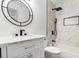 Bright bathroom with a shower/tub combo, marble style tile, modern fixtures, and stylish round mirror at 732 Jamestown Xing, Jonesboro, GA 30238