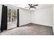 Bedroom with neutral carpet, a ceiling fan, and a large window with dark curtains providing natural light at 732 Jamestown Xing, Jonesboro, GA 30238