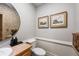 Stylish half bathroom features a wood vanity, round mirror, and framed artwork on the neutral-toned walls at 2610 Ginger Dr, Buford, GA 30519