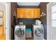 Efficient laundry room equipped with modern stainless steel washer and dryer units and wooden storage cabinets at 2610 Ginger Dr, Buford, GA 30519
