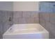 Clean and modern bathtub with stylish gray tile surround and sleek fixtures at 9117 Dearing St, Covington, GA 30014