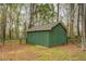 Close up of green outbuilding surrounded by trees and a chain link fence at 9117 Dearing St, Covington, GA 30014