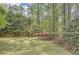 Green backyard and trees surrounding property with small bushes, a few flowers, and a wooden fence at 103 Nob Hl, Peachtree City, GA 30269