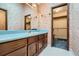 Bathroom with wood vanity, blue countertop, closet, and floral wallpaper at 103 Nob Hl, Peachtree City, GA 30269