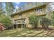 Back exterior view of the home featuring a deck surrounded by lush trees and flowers at 103 Nob Hl, Peachtree City, GA 30269