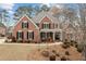 Elegant two-story brick home with manicured landscaping, showcasing a covered front porch and classic architectural details at 214 Cedar Woods Way, Canton, GA 30114