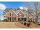 Charming two-story brick home featuring black shutters, mature trees, and a well-manicured lawn, perfect for suburban living at 214 Cedar Woods Way, Canton, GA 30114