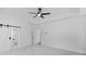 Bright bedroom featuring a ceiling fan, ensuite bath with soaking tub, and sleek barn door at 7043 Foundry Dr, Woodstock, GA 30188
