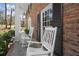 Charming front porch with rocking chairs, perfect for enjoying the outdoors, complemented by brick and black shutters at 495 Heritage Way, Atlanta, GA 30328
