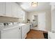 Well-lit laundry room with white cabinets, a sink, and modern washer and dryer units at 495 Heritage Way, Atlanta, GA 30328