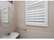 Powder room features a pedestal sink, round mirror, and window with privacy shutters at 923 Port West Dr, Auburn, GA 30011