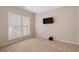Bedroom with neutral walls, carpet, large window with plantation shutters, and a mounted TV at 923 Port West Dr, Auburn, GA 30011