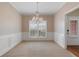 Carpeted dining room featuring large window with plantation shutters and a decorative chandelier at 923 Port West Dr, Auburn, GA 30011