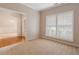 Carpeted living room with neutral walls and a view into the home's entryway at 923 Port West Dr, Auburn, GA 30011