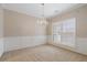 Bright living room with neutral walls, carpet, plantation shutters, and a decorative chandelier at 923 Port West Dr, Auburn, GA 30011