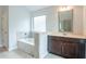 Bathroom featuring a soaking tub, a vanity with a dark wood cabinet, and a large mirror at 3443 Woodshade Dr, Loganville, GA 30052