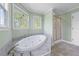 Bathroom featuring an oval soaking tub with jets, a shower, and multiple windows at 190 Ccc Rd, Kingston, GA 30145