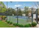Fenced tennis court with green and blue surface surrounded by lush trees on a sunny day at 230 Silver Fox Trl, Dallas, GA 30157