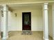 Covered front porch with a brown front door and decorative wall lanterns and supports at 3150 Berkshire Manor Dr, Alpharetta, GA 30022