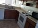 Functional kitchen featuring wood cabinets, white appliances, and a view of the dining area at 340 Teal Ct, Roswell, GA 30076