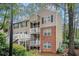 Exterior view of a two-story condo building with brick and siding, featuring outdoor stairs and landscaping at 306 Teal Ct, Roswell, GA 30076