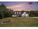 Charming two-story home with manicured lawn and classic white facade, showcased under a beautiful sunset sky at 95 Hawthorn Ln, Covington, GA 30014
