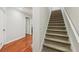 Carpeted stairway with white trim adjoins hallway featuring hardwood floors and a white door at 4062 Vinings Mill Se Trl, Smyrna, GA 30080