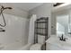 Bathroom with shower/tub combo, white tile, dark fixtures, and storage shelf at 395 Highland Gate Cir, Suwanee, GA 30024