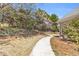 Landscaped backyard with a paved pathway leading alongside the home, enhanced by flowering trees and mature shrubs at 4090 Cherry Ridge Walk, Suwanee, GA 30024