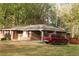 Quaint brick home with a mature lawn, featuring a driveway and a red SUV parked in front at 1185 Highway 162, Covington, GA 30016