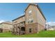 View of the two-story home's backyard, featuring a deck and brick foundation, set against a blue sky at 245 Piedmont Cir, Covington, GA 30016