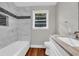Bathroom with tub, marble tile surround, accent tile, white vanity, and hardwood floors at 111 Leathers Circle Nw, Atlanta, GA 30314