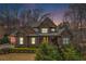 Brick two-story home featuring warm exterior lighting, a well-maintained lawn, and mature trees at 1190 Mosspointe Dr, Roswell, GA 30075