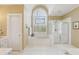 Elegant bathroom with large arched window, soaking tub, and glass enclosed shower at 6840 N Creekside Pt, Cumming, GA 30041
