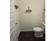 A compact powder room features dark wood floors, a white toilet, and rustic shelves for an efficient design at 184 Grafton St, Hampton, GA 30228