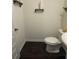 A compact powder room features dark wood floors, a white toilet, and rustic shelves for an efficient design at 184 Grafton St, Hampton, GA 30228