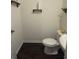 A compact powder room features dark wood floors, a white toilet, and rustic shelves for an efficient design at 184 Grafton St, Hampton, GA 30228