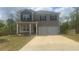 Charming two-story home featuring gray siding, dark shutters, a well-manicured lawn, and a spacious two-car garage at 184 Grafton St, Hampton, GA 30228