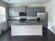 This spacious kitchen features gray cabinets, granite countertops, stainless steel appliances and a large island at 184 Grafton St, Hampton, GA 30228